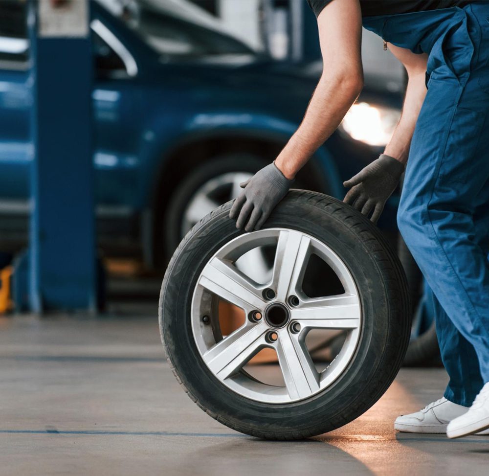 close-up-view-man-work-uniform-with-car-wheel-indoors-conception-automobile-service-image